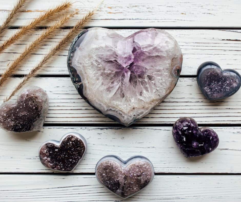 A picture of several amethyst crystal hearts with some tufts of wheat