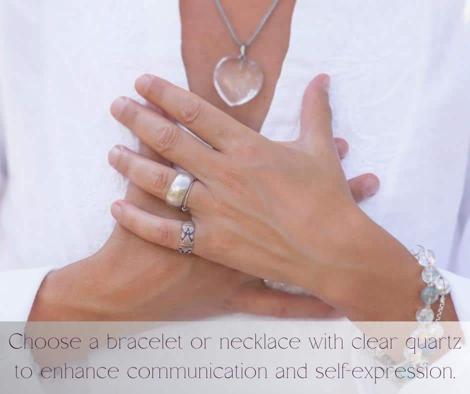 A picture of a ladies hands to her chest with a  quartz crystal heart necklace 